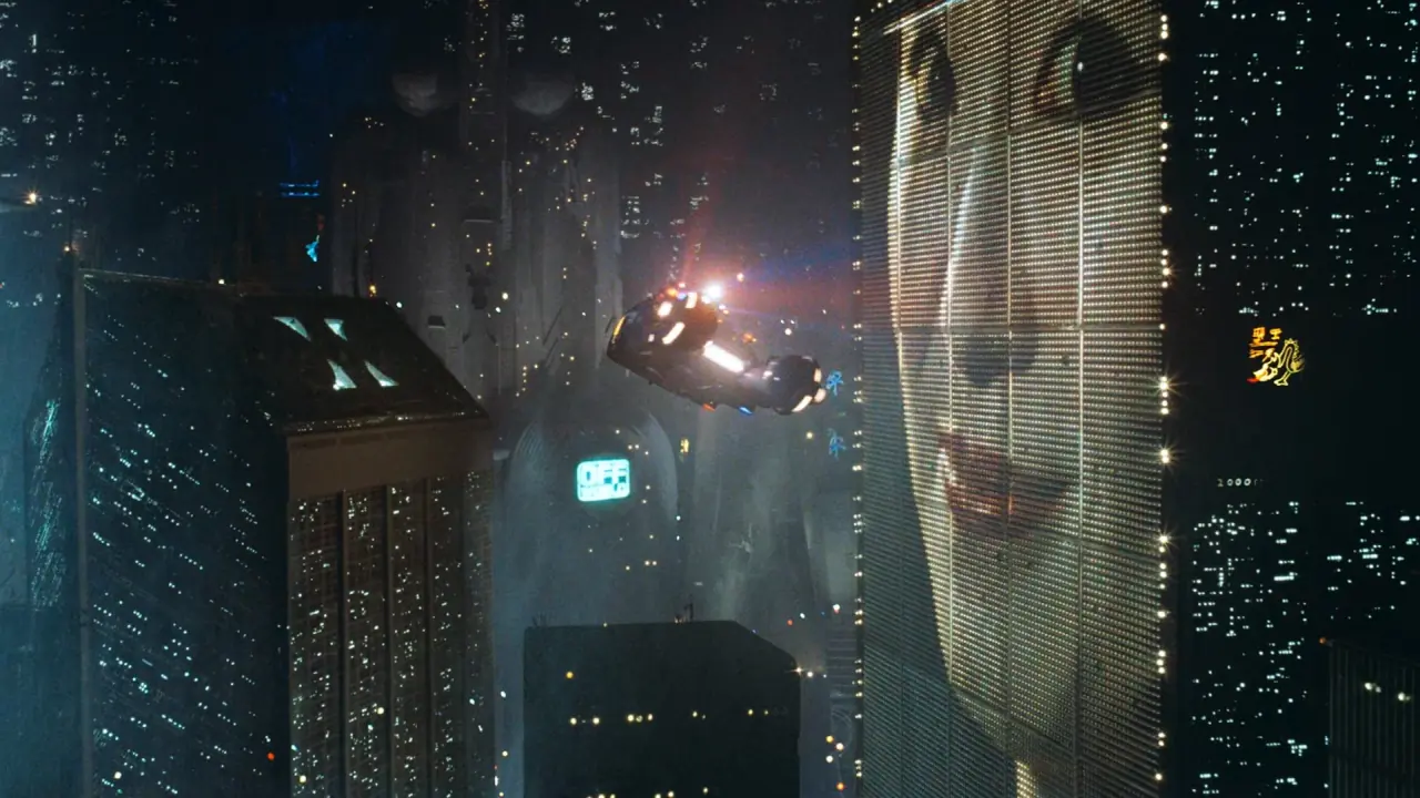 Image from the 1982 sci-fi film "Blade Runner," produced by The Ladd Company, featuring a futuristic urban landscape with neon lights and towering skyscrapers, evoking the film's dystopian themes.